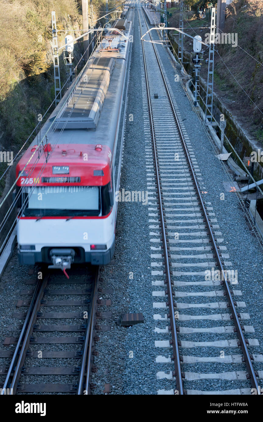 One point perspective view of a couple of railways with a moving red and white train in Guipuzcoa (Spain) 2017. Stock Photo