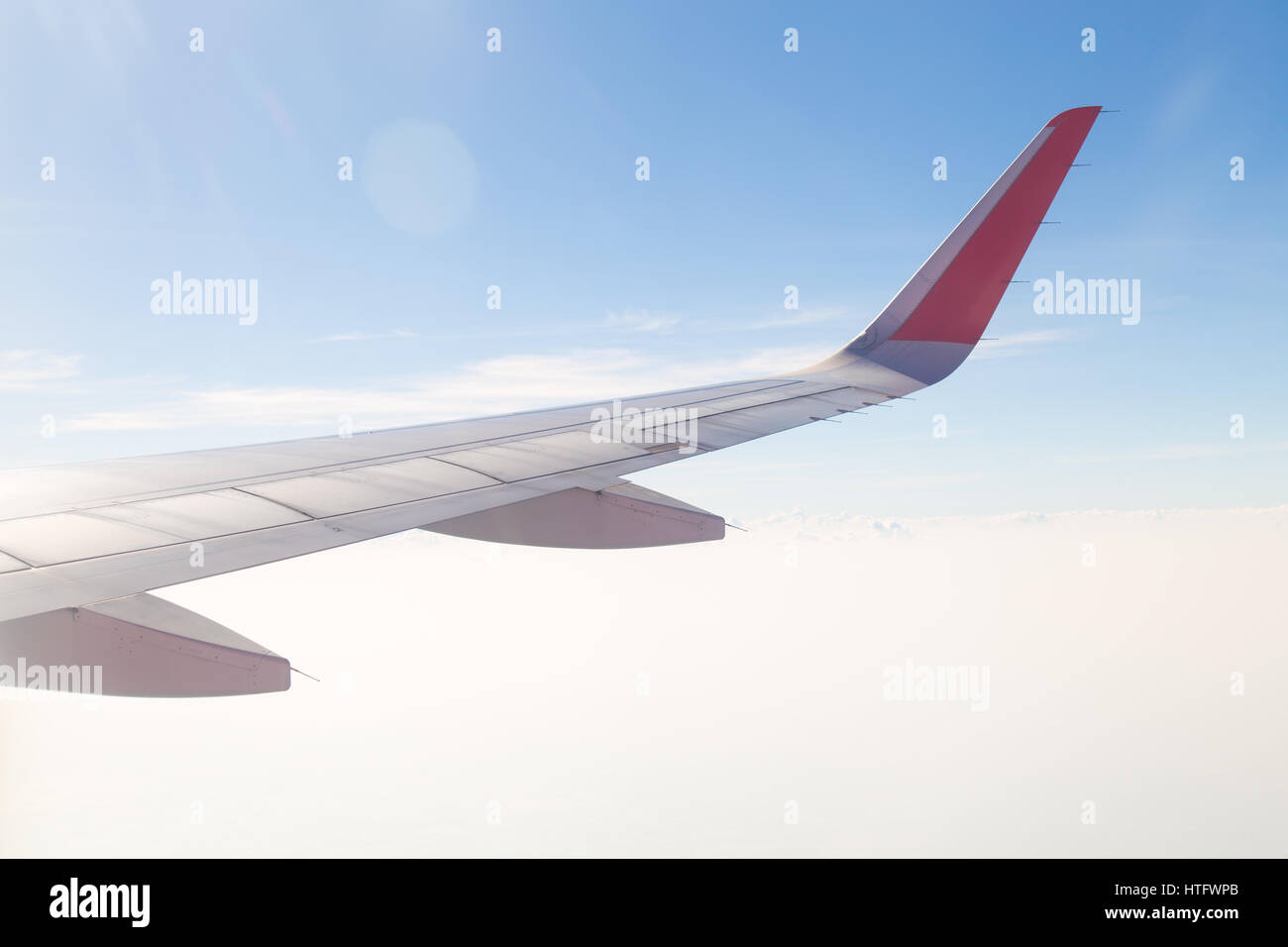 Wing of an airplane flying above the blue sky and clouds Stock Photo ...