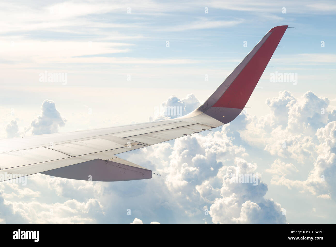 Wing of an airplane flying above the blue sky and clouds Stock Photo ...