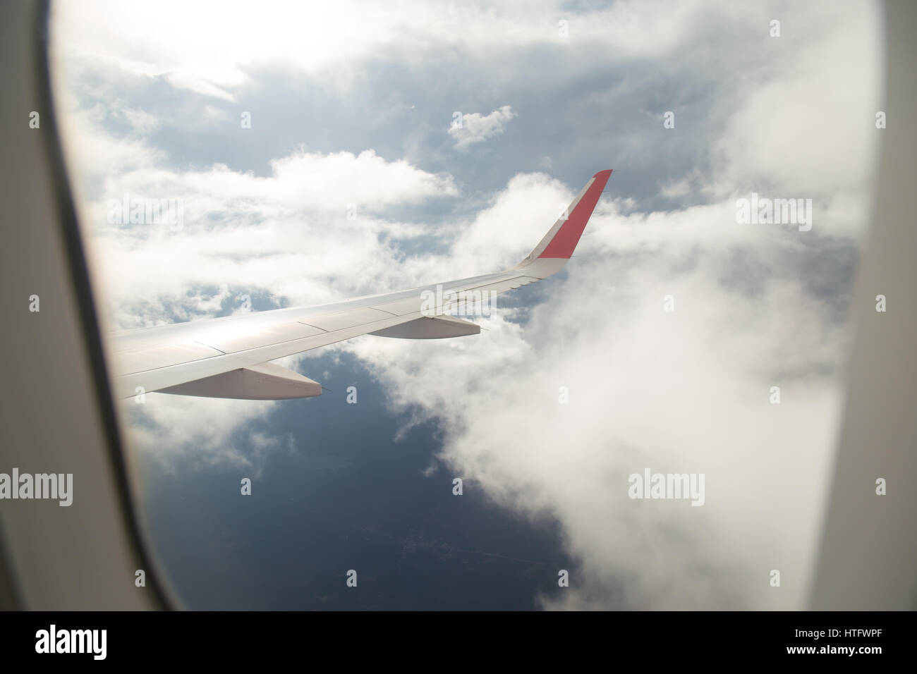 Wing of an airplane flying above the blue sky and clouds Stock Photo ...