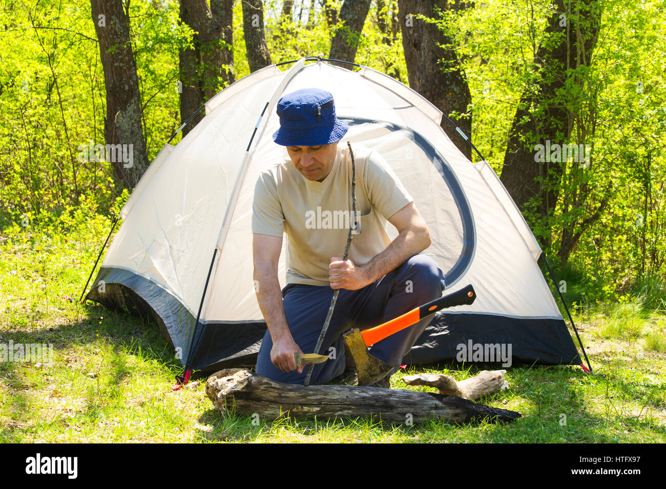 Man chopping wood to tent Stock Photo - Alamy