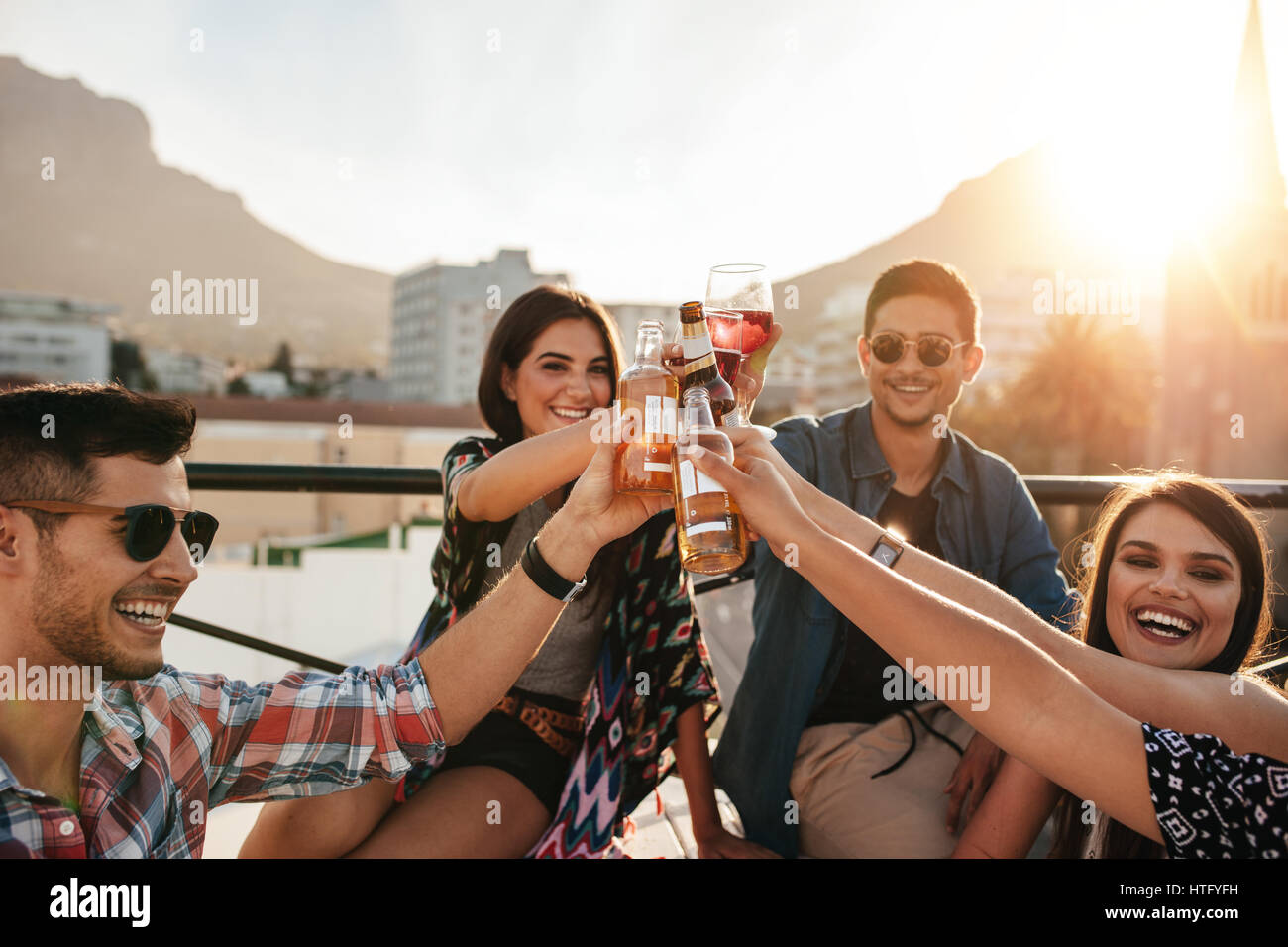 Friends having fun and drinking outdoor on a rooftop get together. Group of friends hanging out and toasting drinks outdoors. Stock Photo