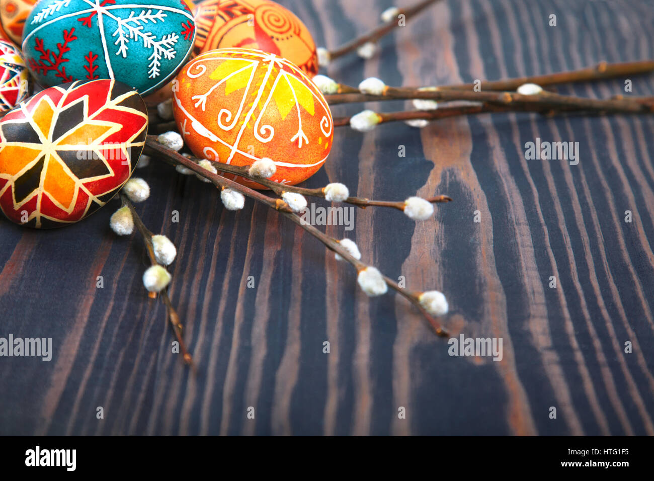 Easter eggs with willow twigs on a wooden plank table. The concept of ...