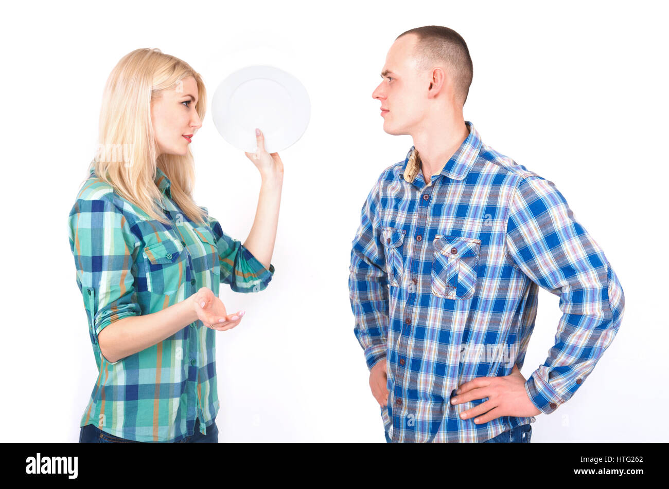 A man and a young woman with a plate in her hand quarrel in a studio on a white background. Stock Photo