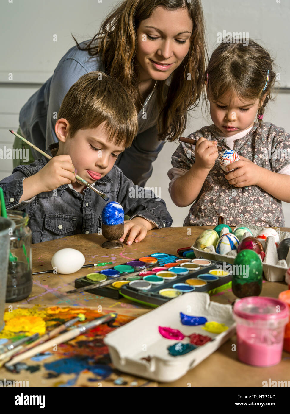 Photo of a mother and her children painting and decorating hardboiled