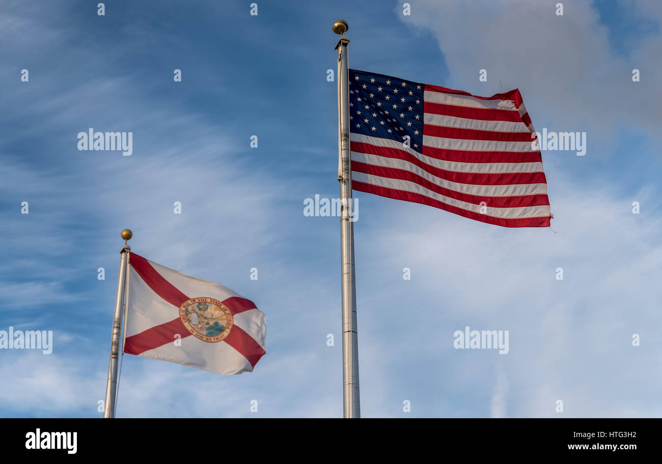 The Florida state flag and the US Flag (the Starts and Stripes) flying next to each other, against a blue, summers sky Stock Photo