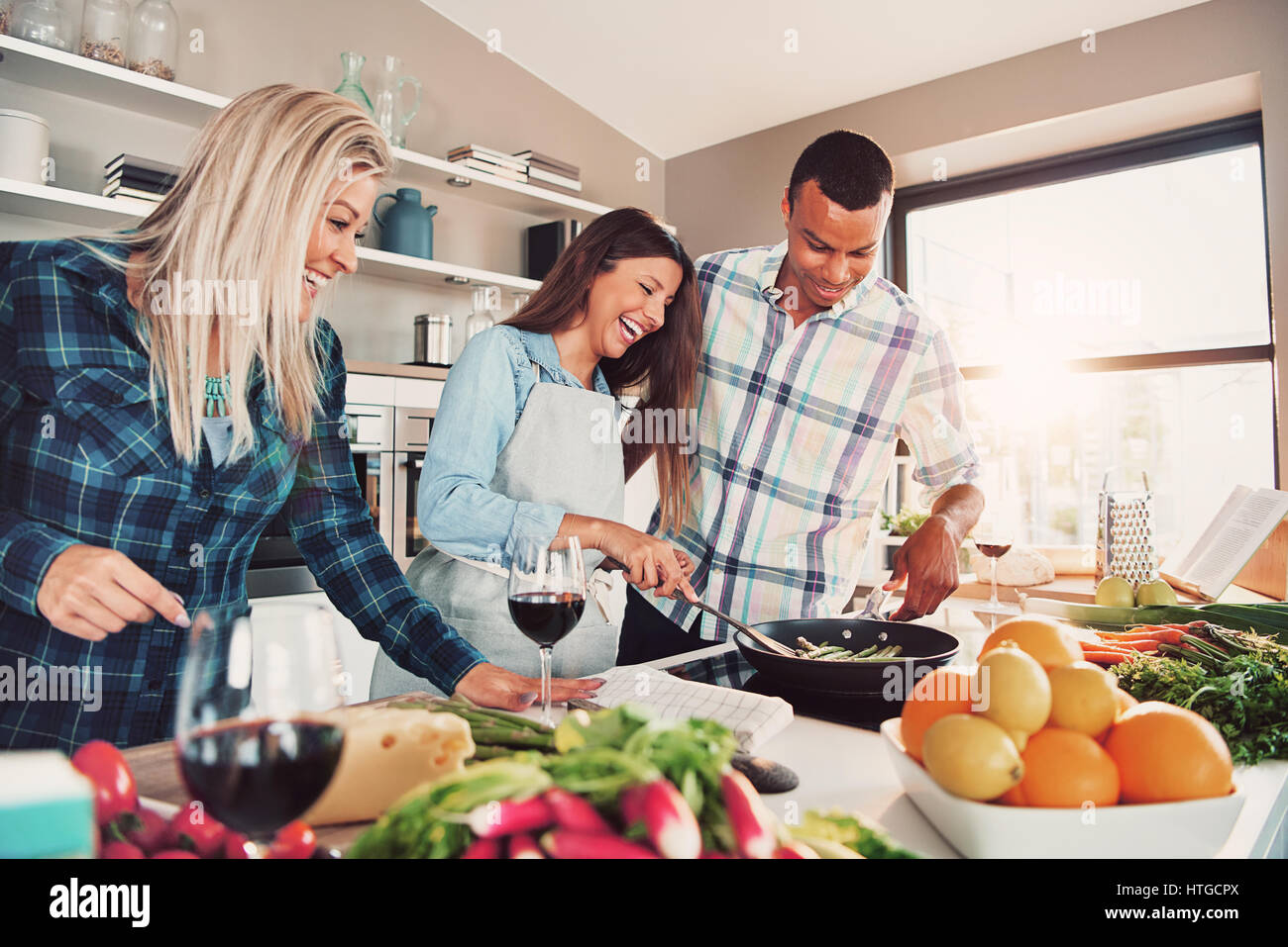 Portrait of three people at kitchen cooking and having fun Stock Photo