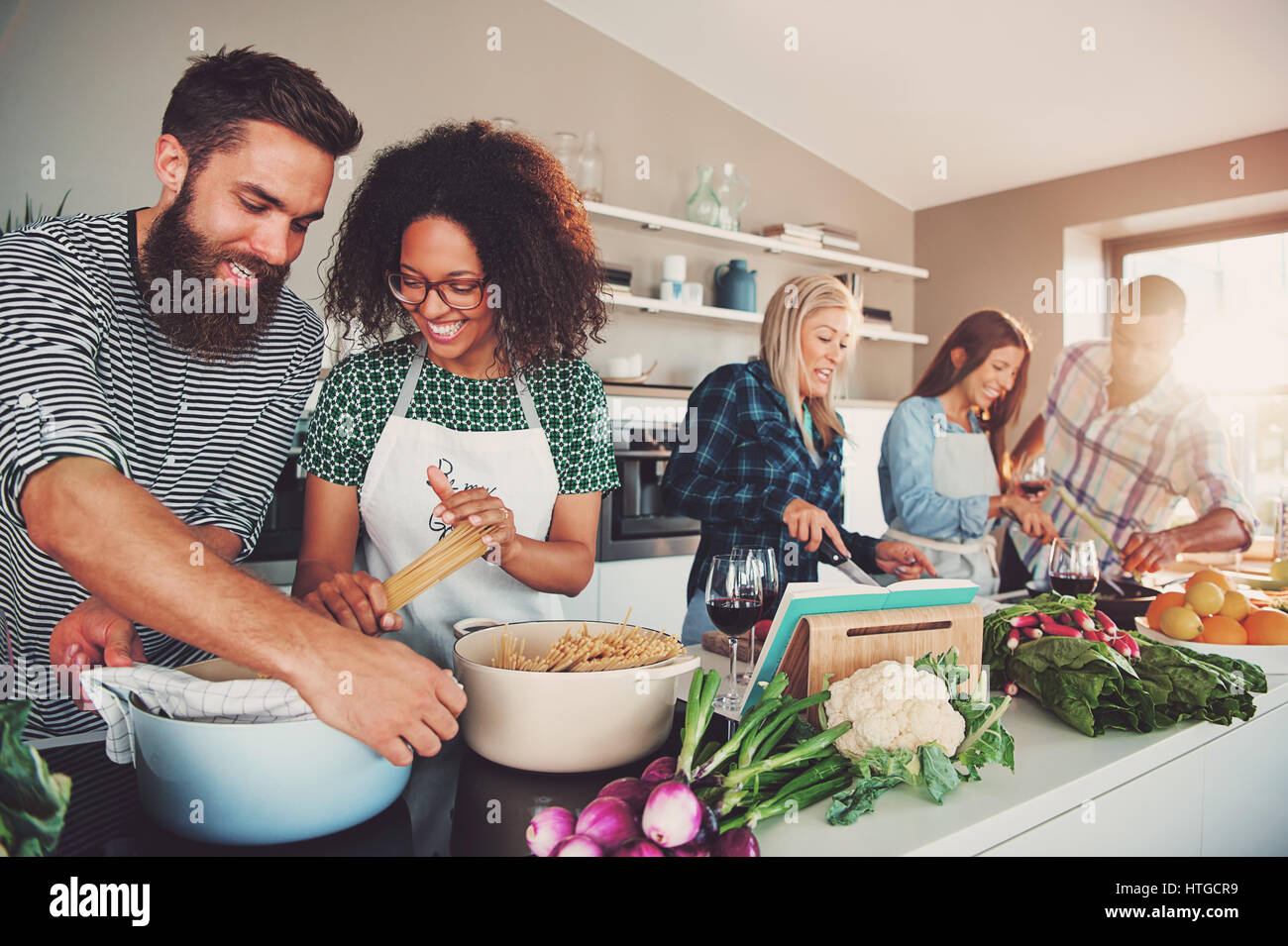 Five friends cheerfully cooking for an upcoming party Stock Photo