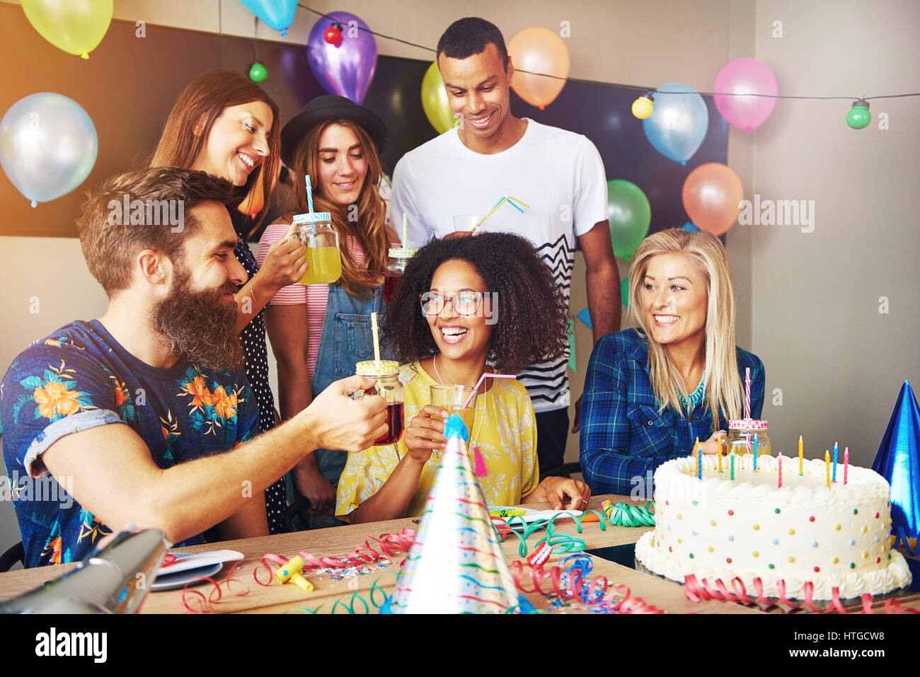 Group of friends celebrating a birthday for party indoors. Colorful baloons and decorations 