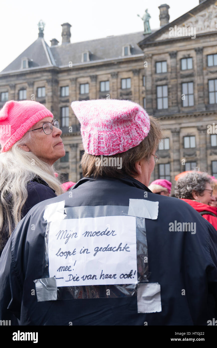 Amsterdam, the Netherlands. 12th March, 2017. Two older ladies carry pink knitted hats. One has a sign on her back that says 'My mom walks with us in her thoughts! And <<< her's too! ' Credit: Steppeland/Alamy Live News Stock Photo