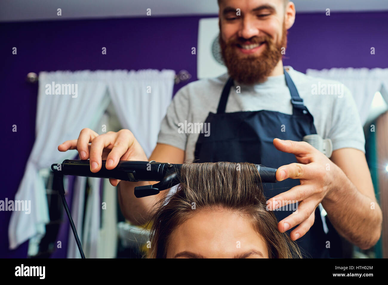 Close-up concept hairdresser barbershop.Barber stylist makes a hair curl. Stock Photo