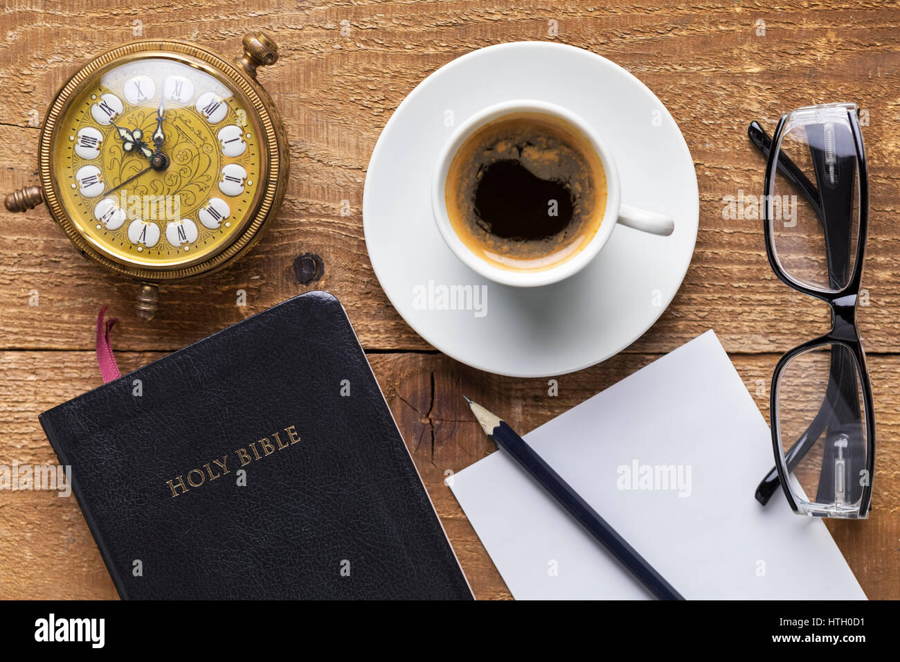 Holy Bible, alarm clock, glasses and coffee on wood table. Studying  the Bible concept. Focus on the Bible Stock Photo