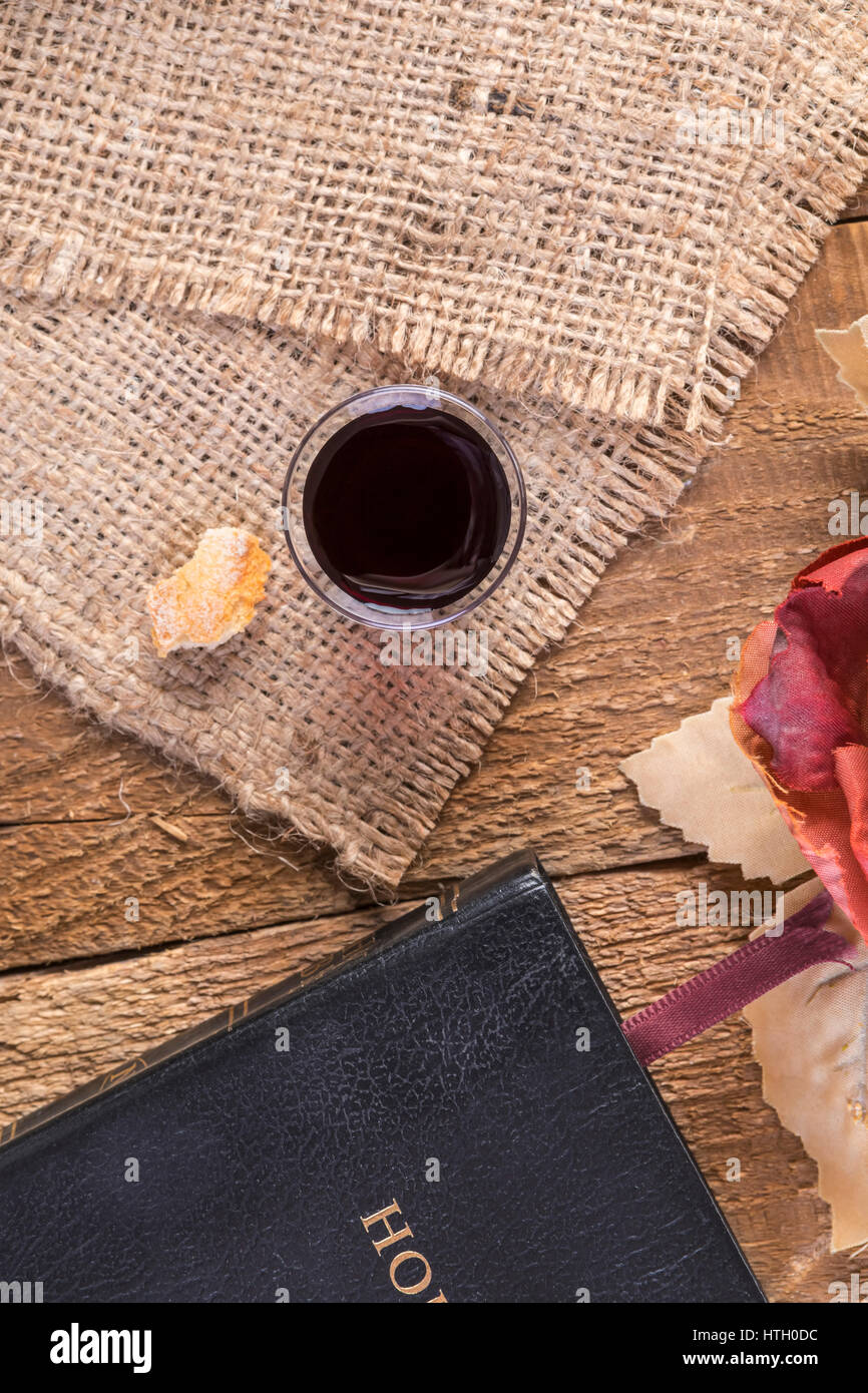 Taking Communion. Cup of glass with red wine, bread and Holy Bible on wooden table close-up Stock Photo