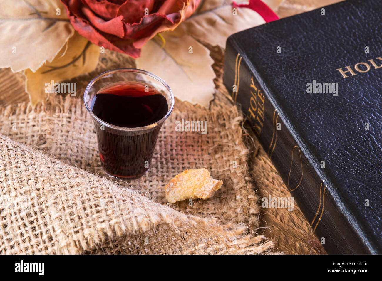 Taking Communion. Cup of glass with red wine, bread and Holy Bible on
