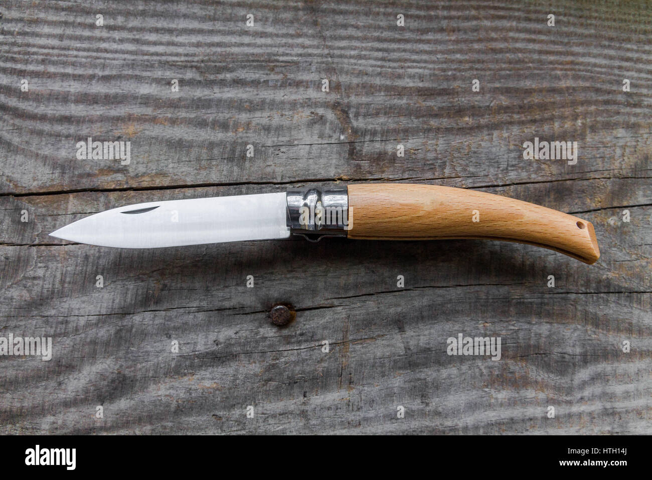 Pocket knife with a wooden handle. The knife is placed diagonally. Wooden background. Stock Photo