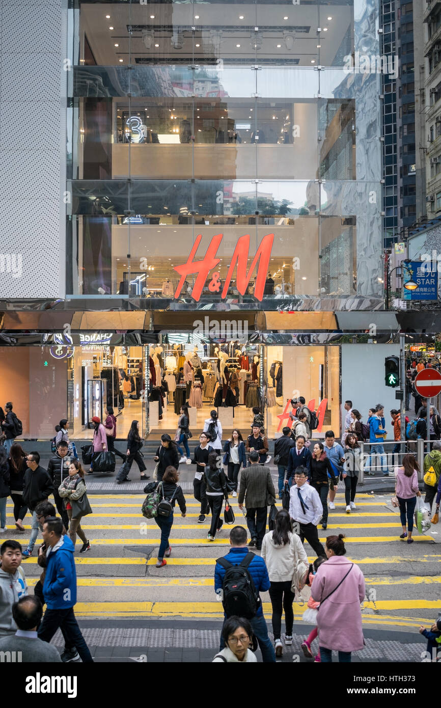 Pedestrians in busy shopping district zebra crossing H&M in background in Hong Kong Stock Photo