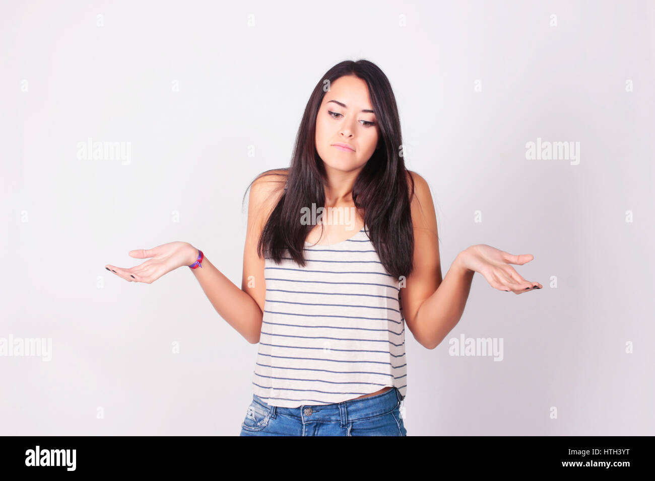 Young woman shrugging her shoulders. Portrait of a woman with clueless expression. Stock Photo