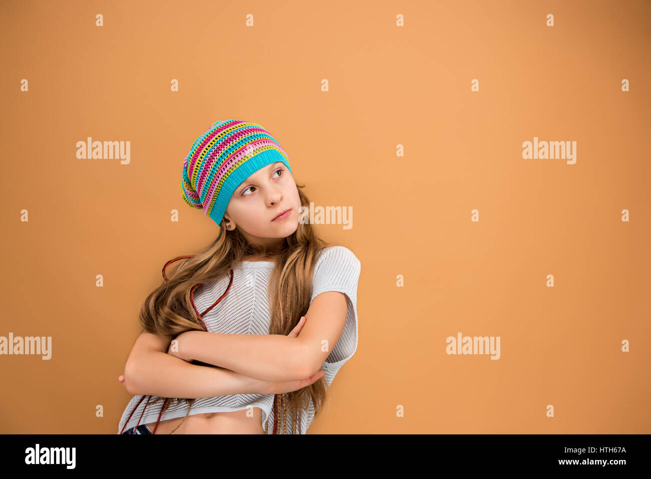 The face of sad teen girl in hat on brown studio background Stock Photo