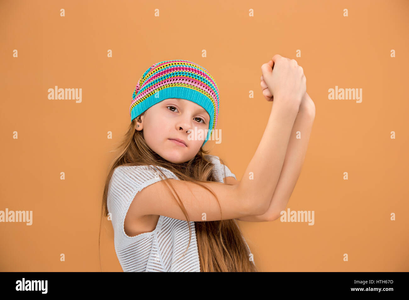The face of sad teen girl in hat on brown studio background Stock Photo