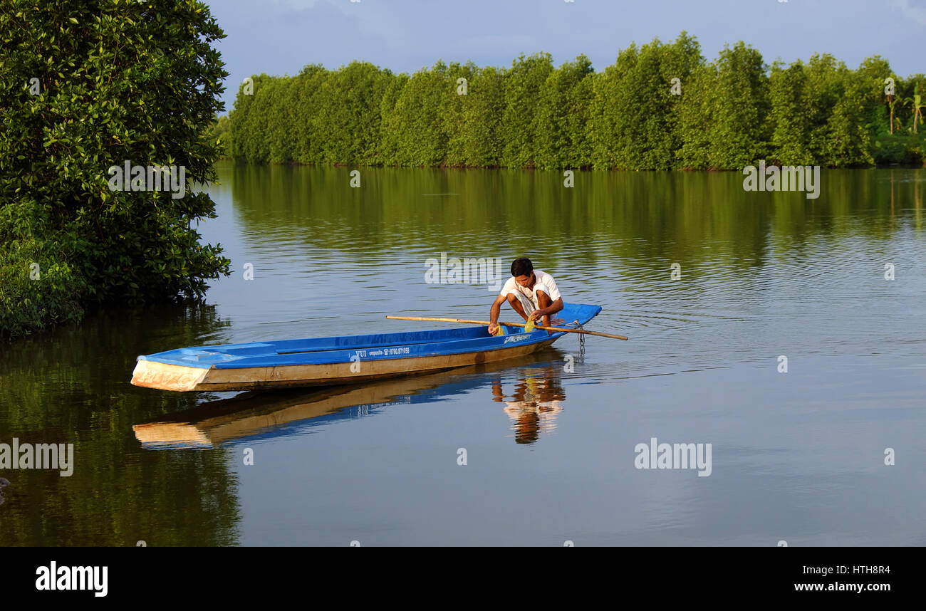 Ca Mau, Viet Nam, Vietnamese man catch fish on river, fisherman sit on row boat reflect on water, beautiful mangrove forest make wonderful scene Stock Photo