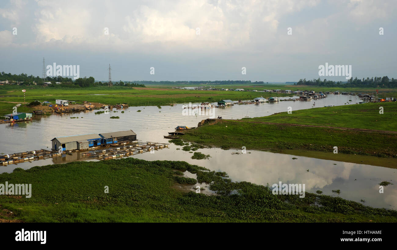 DONG NAI, VIET NAM- JUNE 5: Group of floating house on La Nga fishing village, river with green grass and hyacinth, residence of people who live with  Stock Photo