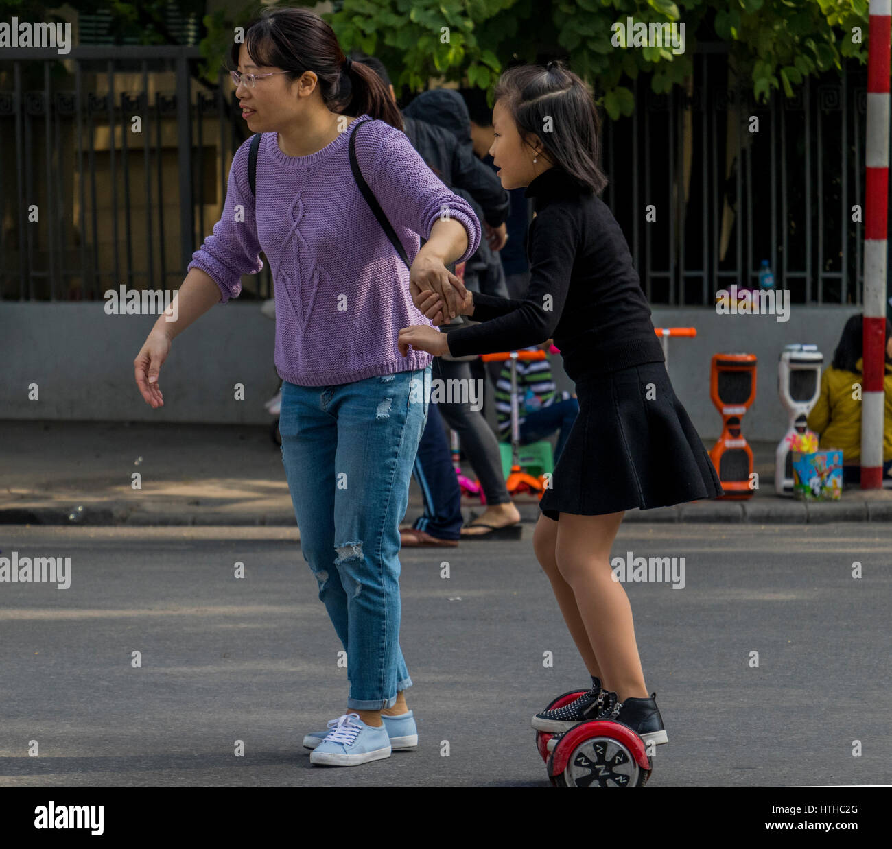 Children with parents playing on streets of Hanoi in Vietnam Stock Photo
