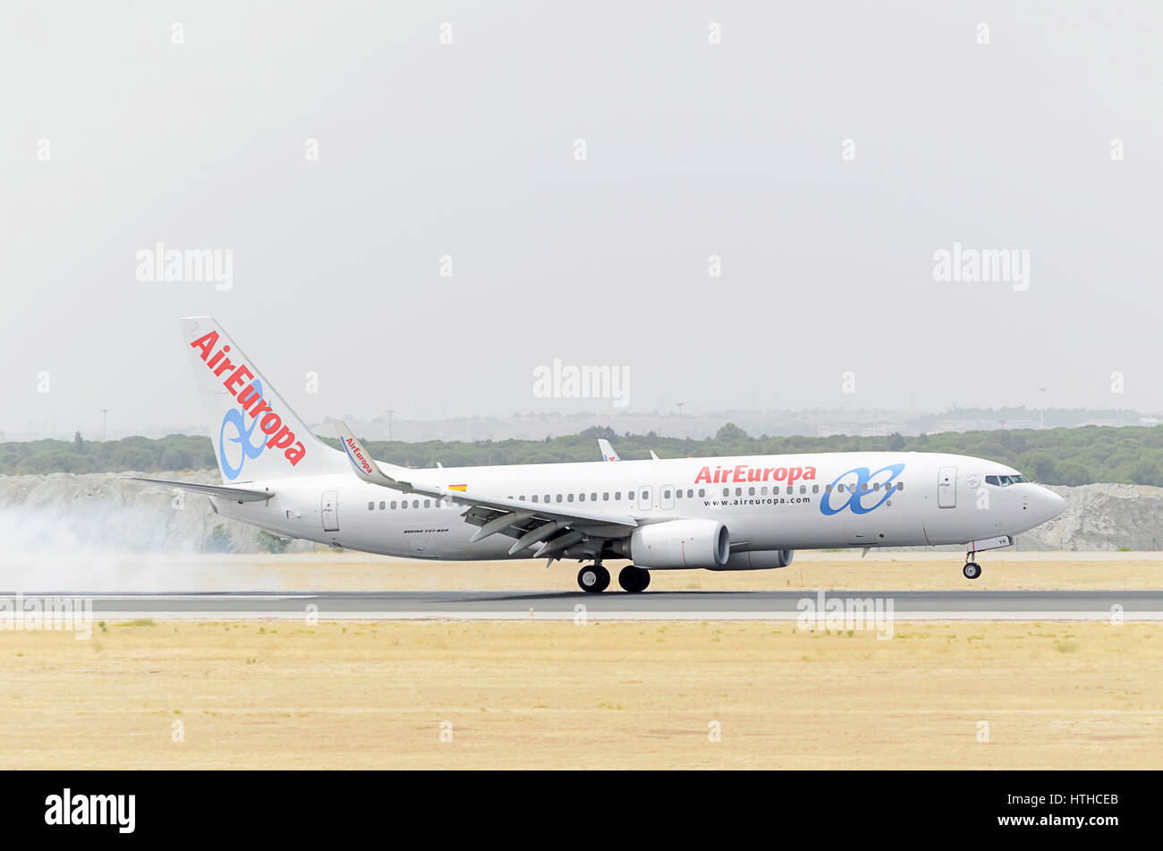 Plane Boeing 737, of Air Europa airline, is landing on Madrid - Barajas, Adolfo Suarez airport. Smoke. Cloudy and hot day of summer. Stock Photo