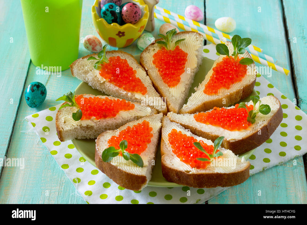 Easter carrot is a sandwich. Creative breakfast for children from bread, butter, red caviar and corn lettuce on a wooden background. Stock Photo