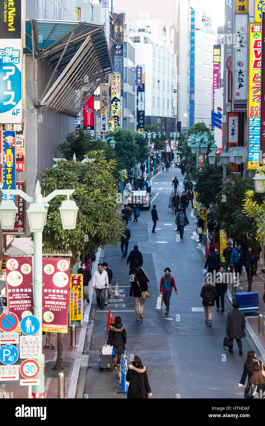 Shoppers and commuters walking along a narrow lane near Shinjuku Train Station, Tokyo, Japan. Stock Photo