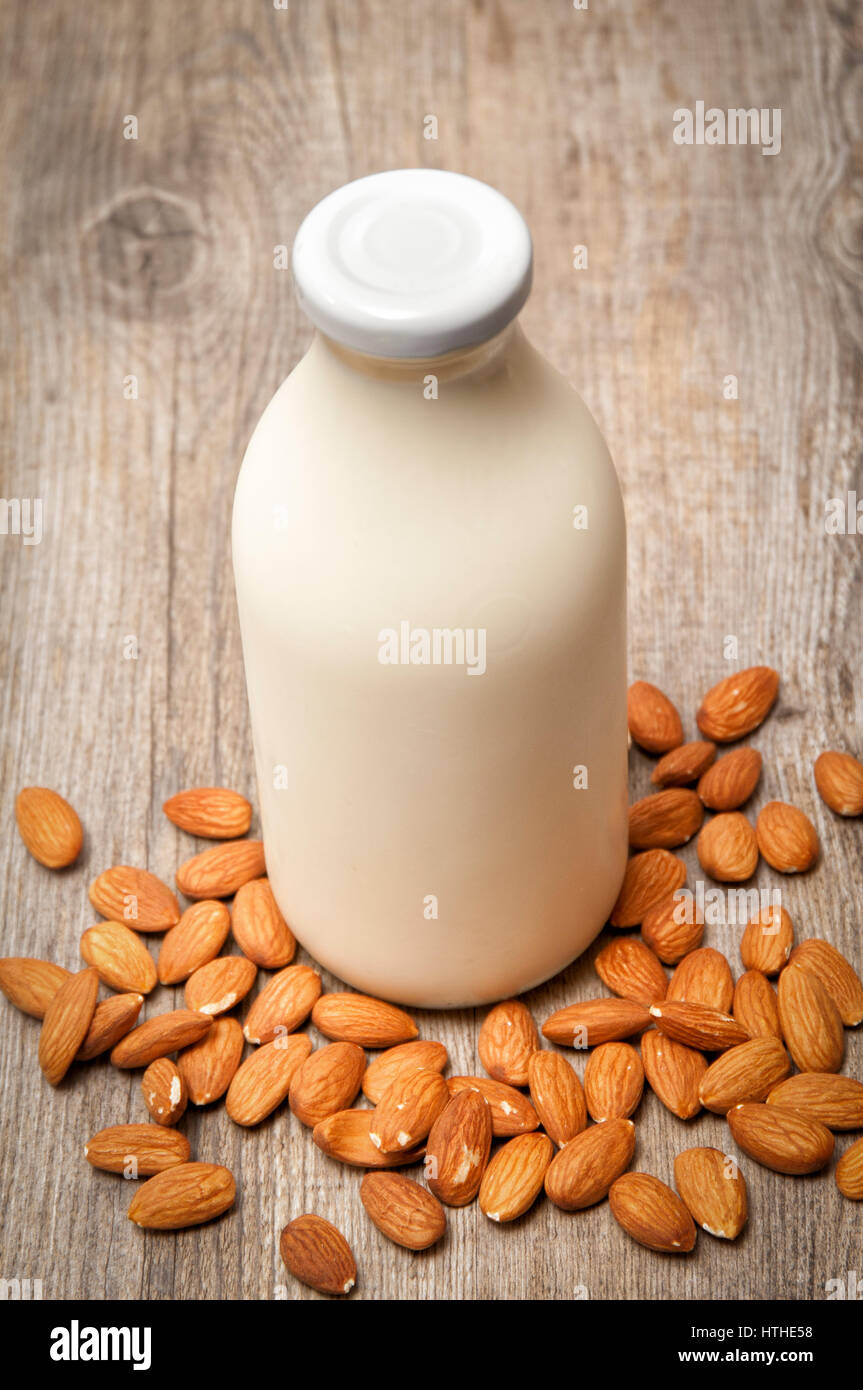 Bottle of hommade almond milk on wooden table with whole almonds Stock Photo