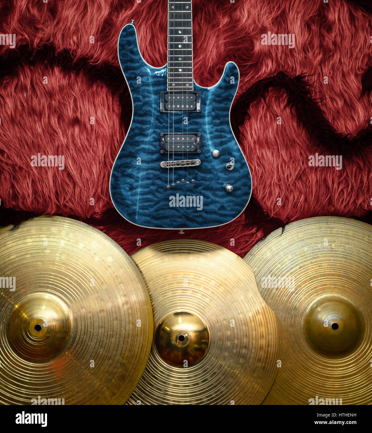 Blue electric guitar with three cymbals on faux fur wall. Musical ...