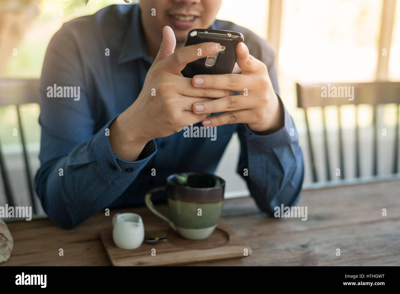 Young businessman using smartphone for social network while sitting in coffee shop. Freelance online working from anywhere concept Stock Photo