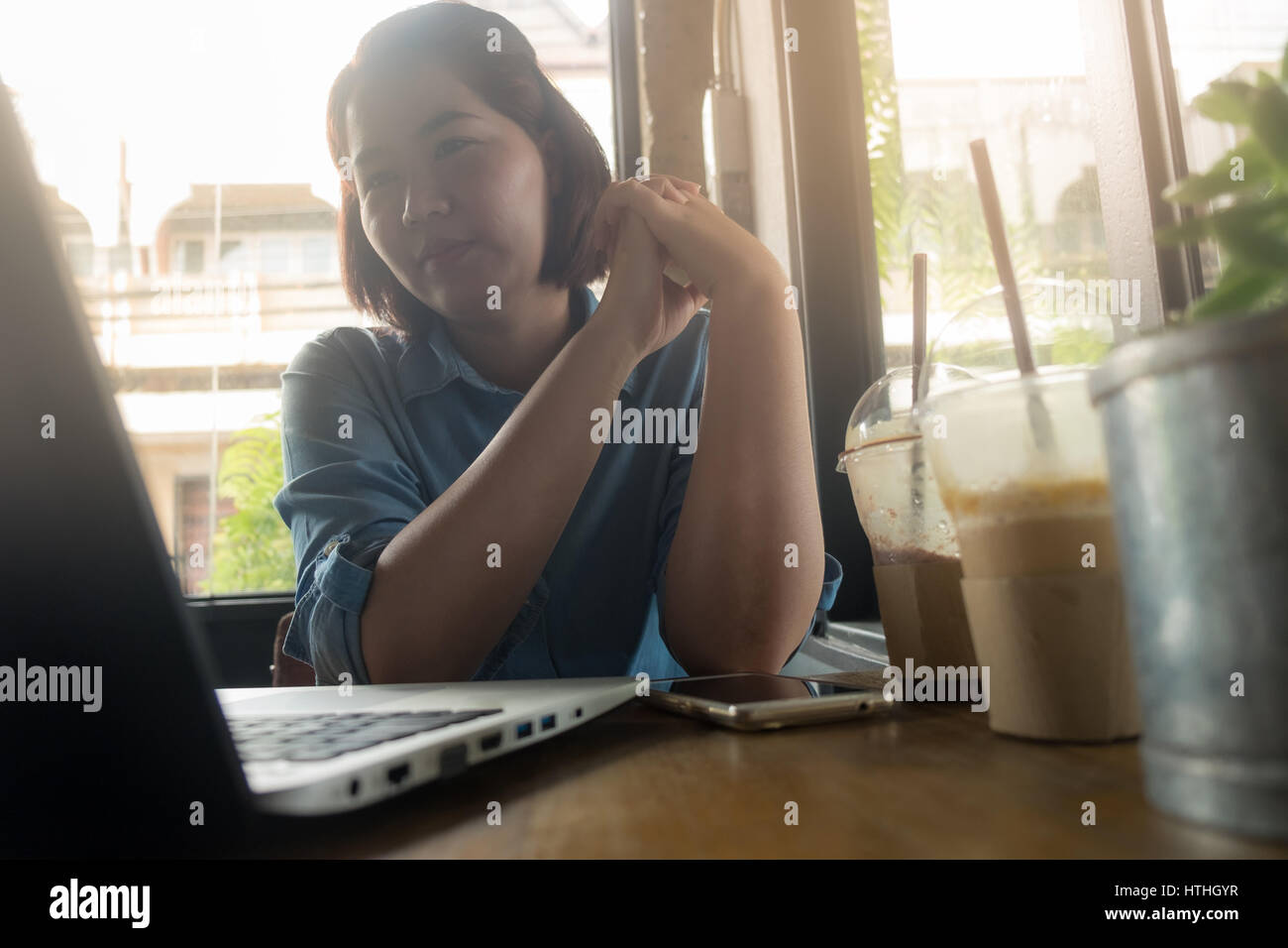Young Asian woman looking at her laptop computer while working in coffee shop. Freelance worker with online business activity concept Stock Photo
