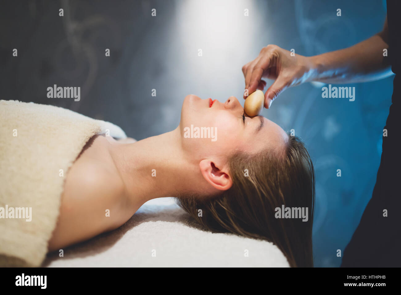Masseur massaging face with heated wooden objects Stock Photo