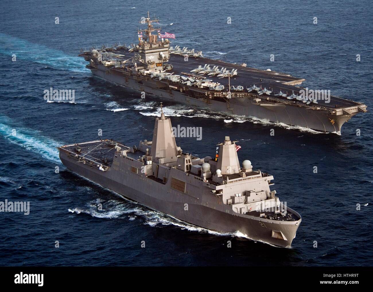 The USN San Antonio-class amphibious transport dock ship USS New York (left) steams in formation alongside the USN Nimitz-class aircraft carrier USS Enterprise June 9, 2012 in the Persian Gulf. Stock Photo