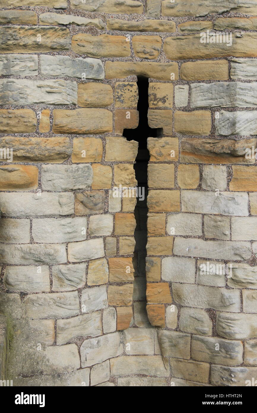 Arrow-slit aperture in the curtain wall of Warkworth Castle, Warkworth, Northumberland, England, UK Stock Photo