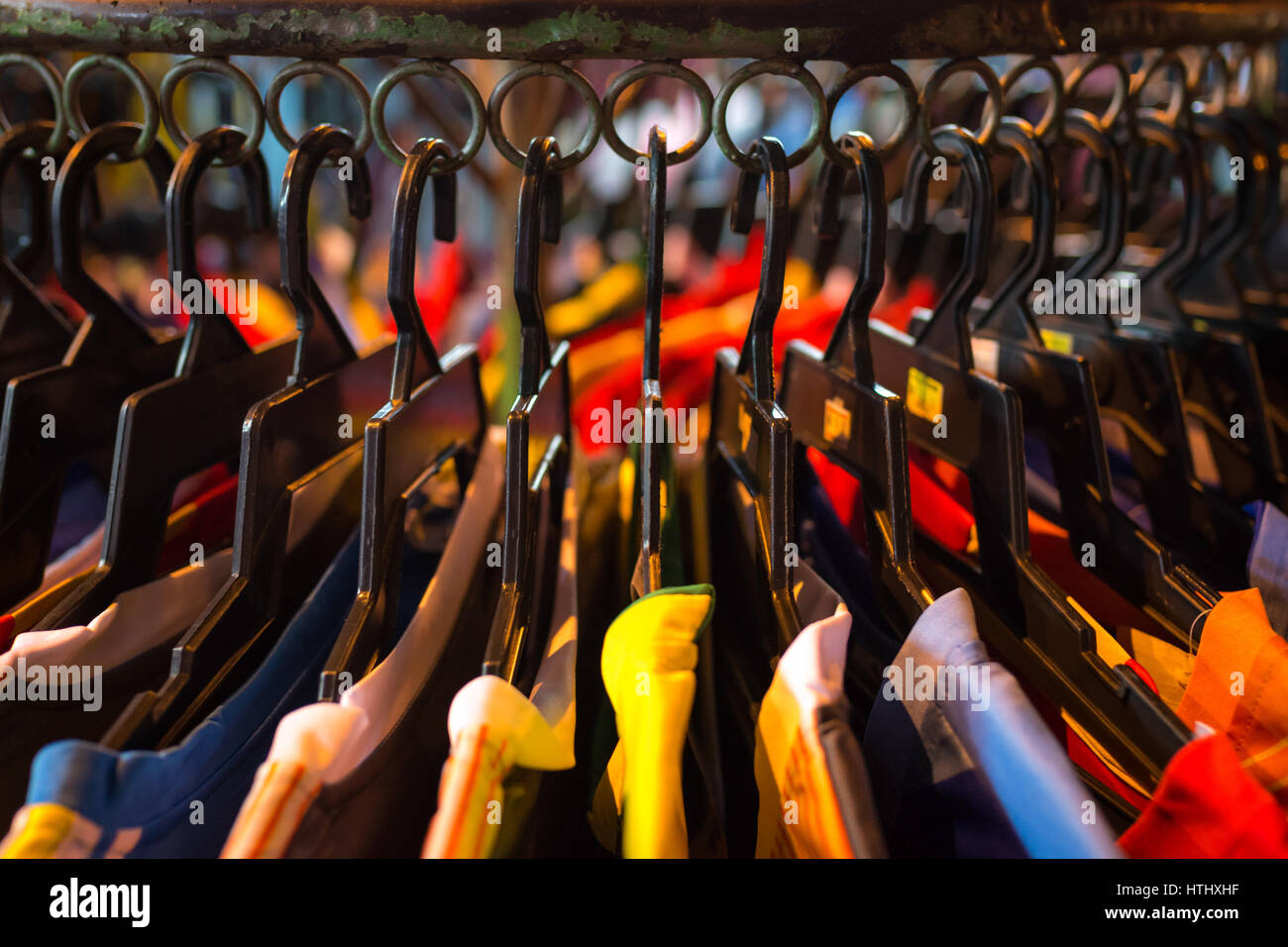 T-shirts and tops hanging on a clothes rail an Asian night market. Stock Photo