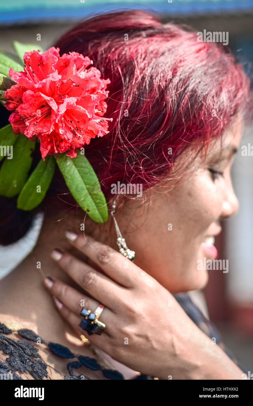 A woman wears a red rhododendron behind her ear. Stock Photo