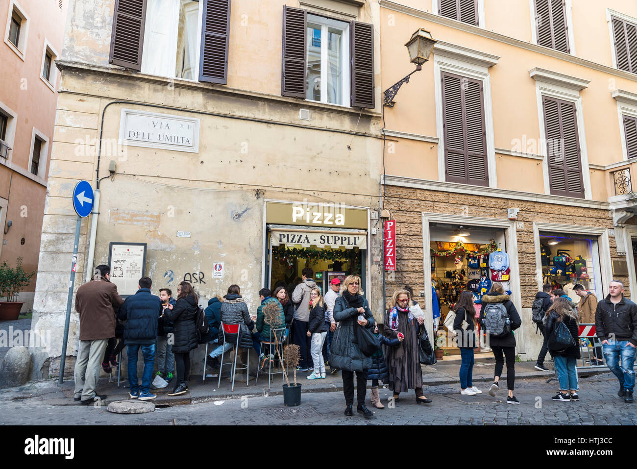 Rome, Italy - December 31, 2016: People walking and eating pizza in a bar on the street in the historical center of Rome, Italy Stock Photo