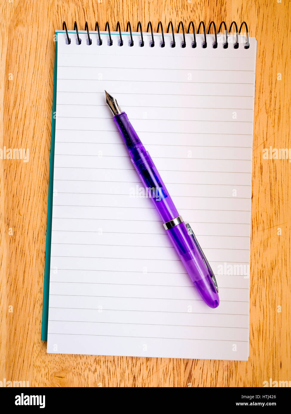 A cheap fountain pen using standard size, international small cartridges on a spiral bound notebook. Stock Photo