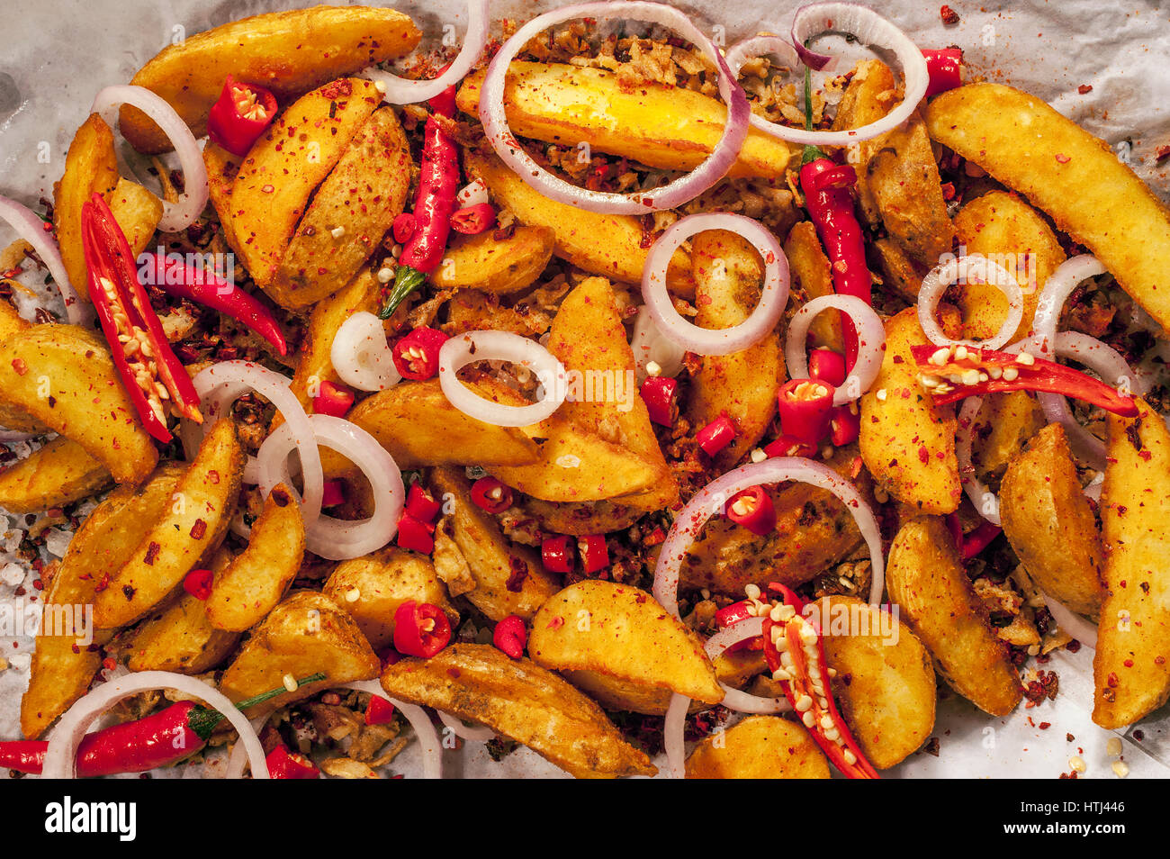 Roasted potato wedges with herbs and red peppers Stock Photo