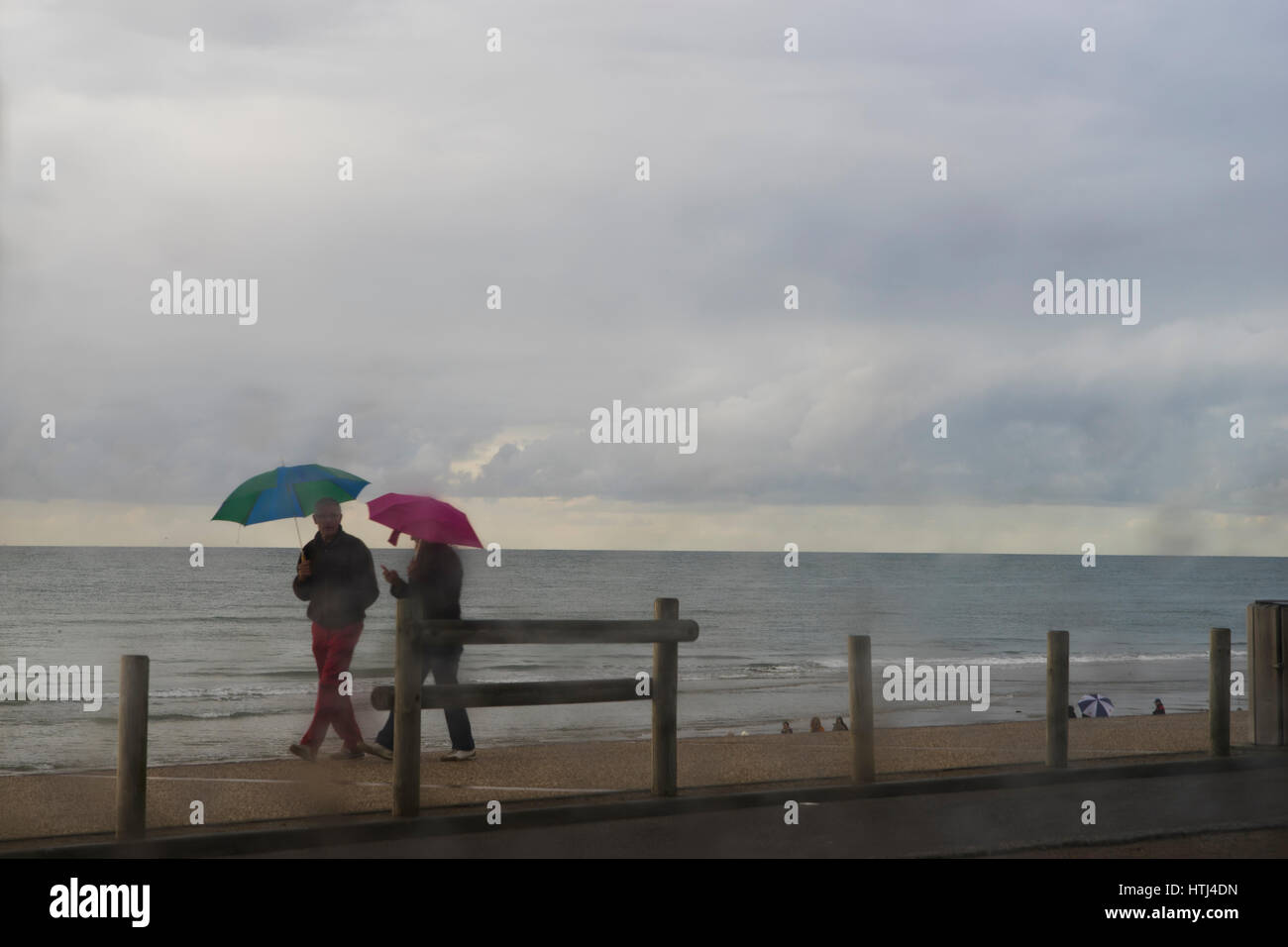 tourists with umbrellas during a rain shower on the promenade at Hardelot beah, Cote d'Opale, France Stock Photo