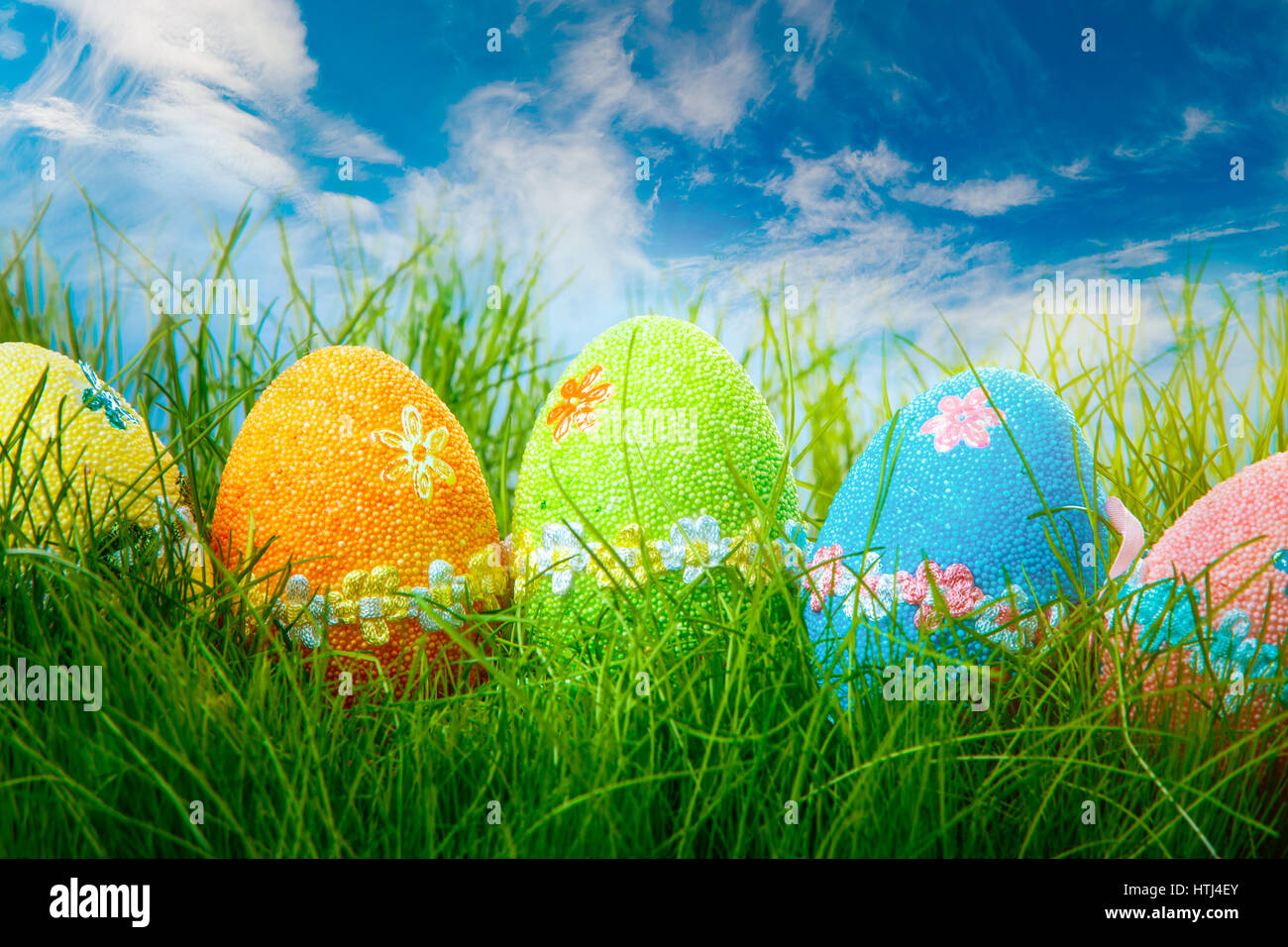Decorated easter eggs in the grass on blue sky background Stock Photo ...