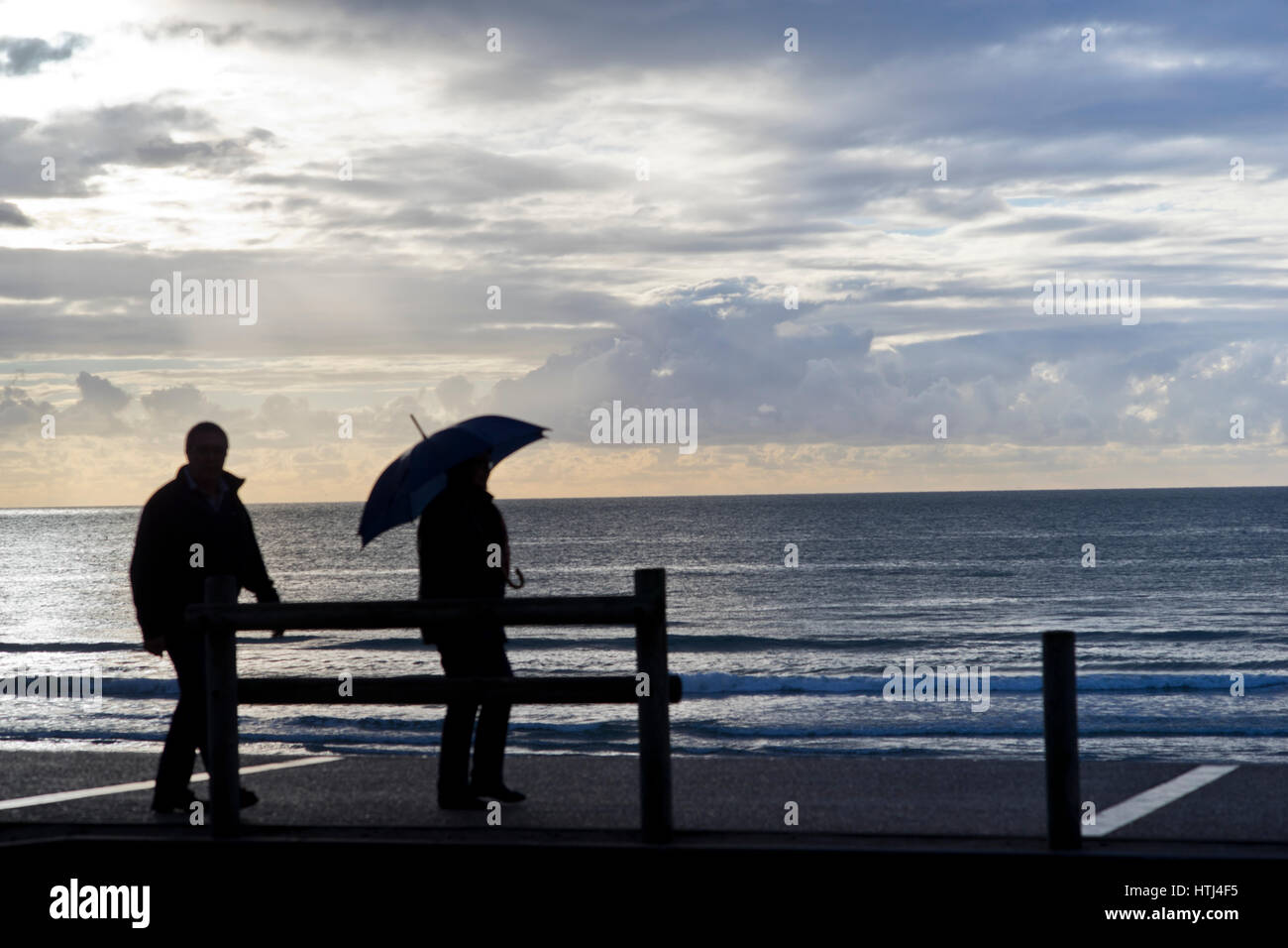 tourists with umbrellas during a rain shower on the promenade at Hardelot beah, Cote d'Opale, France Stock Photo