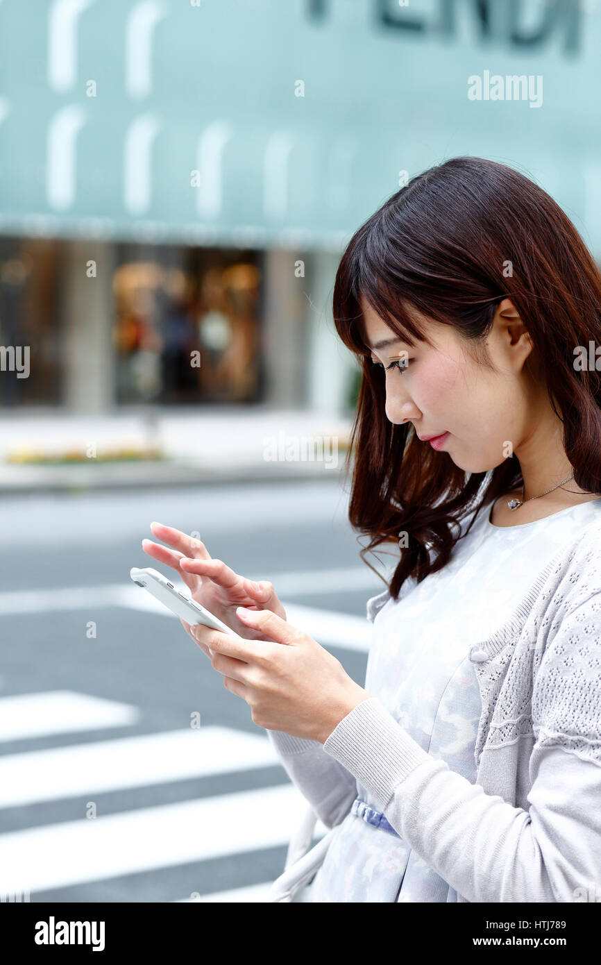 Fashionable Japanese woman with smartphone in luxury Tokyo area, Tokyo, Japan Stock Photo