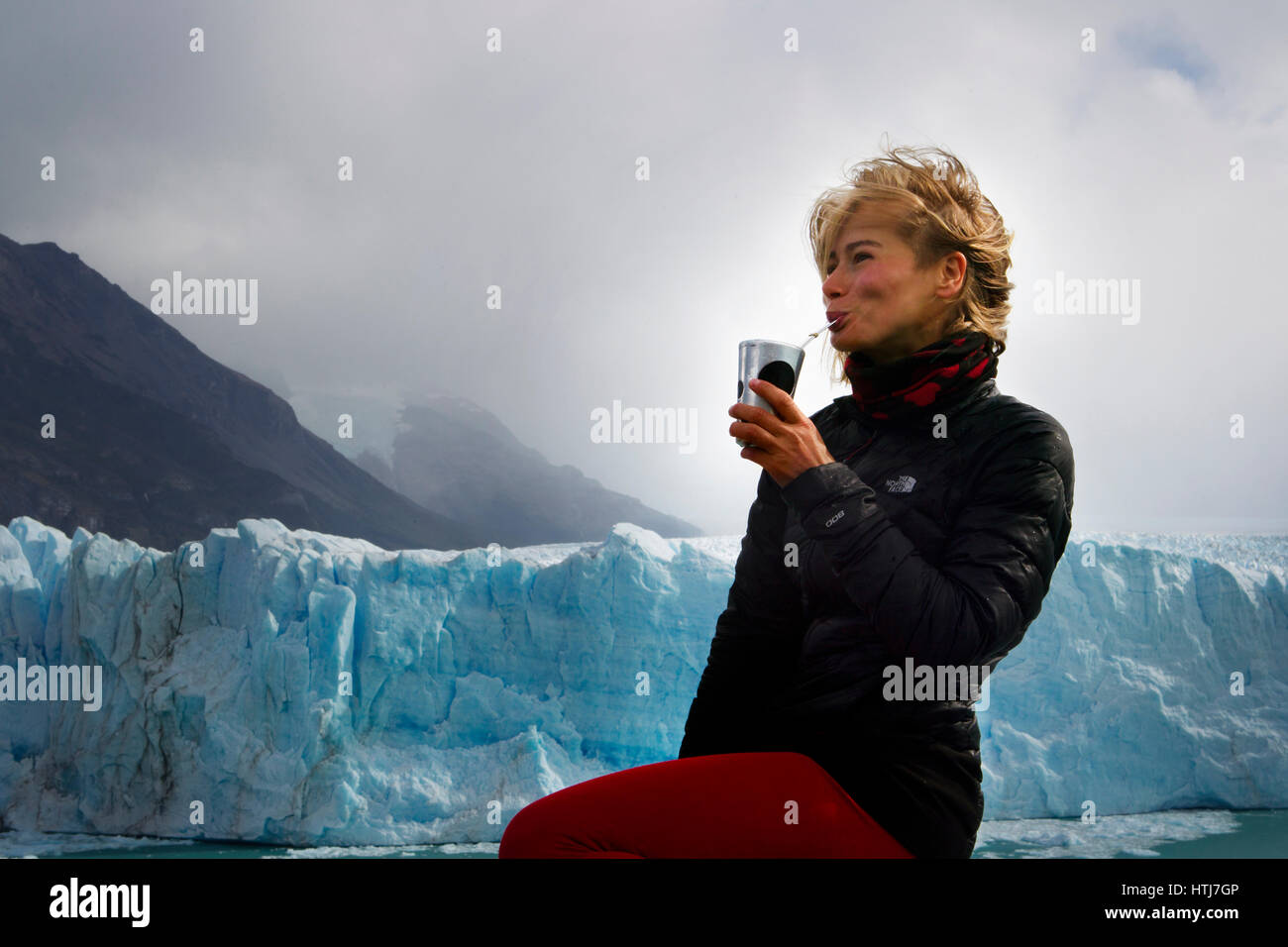 Young european appearances woman drinking mate on a background of the Perito Moreno Glacier, Patagonia, Argentina, South America Stock Photo