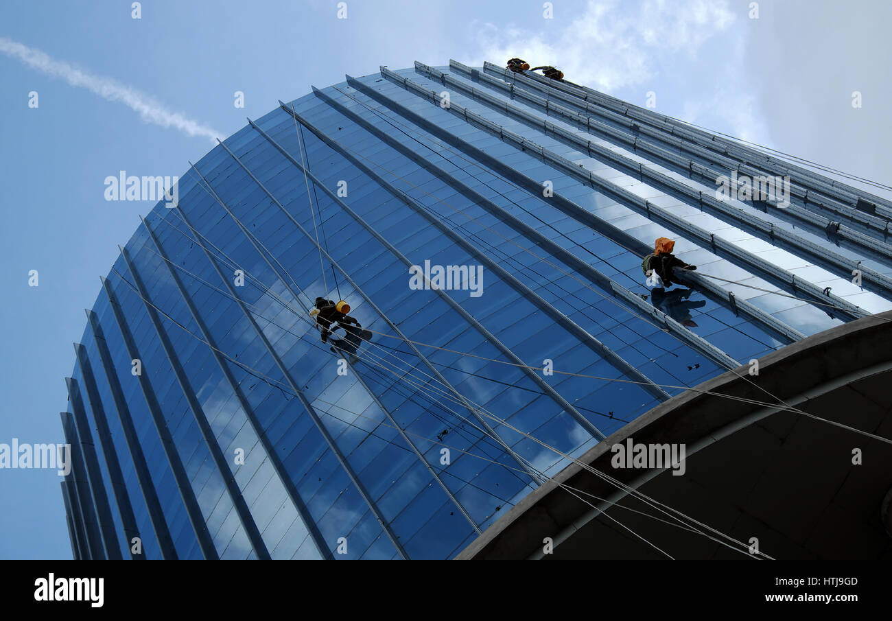 HO CHI MINH CITY, VIET NAM- MAY 30, 2016: Group of Asian construction worker working on highrise building, Vietnamese man climb, clean glass surface o Stock Photo