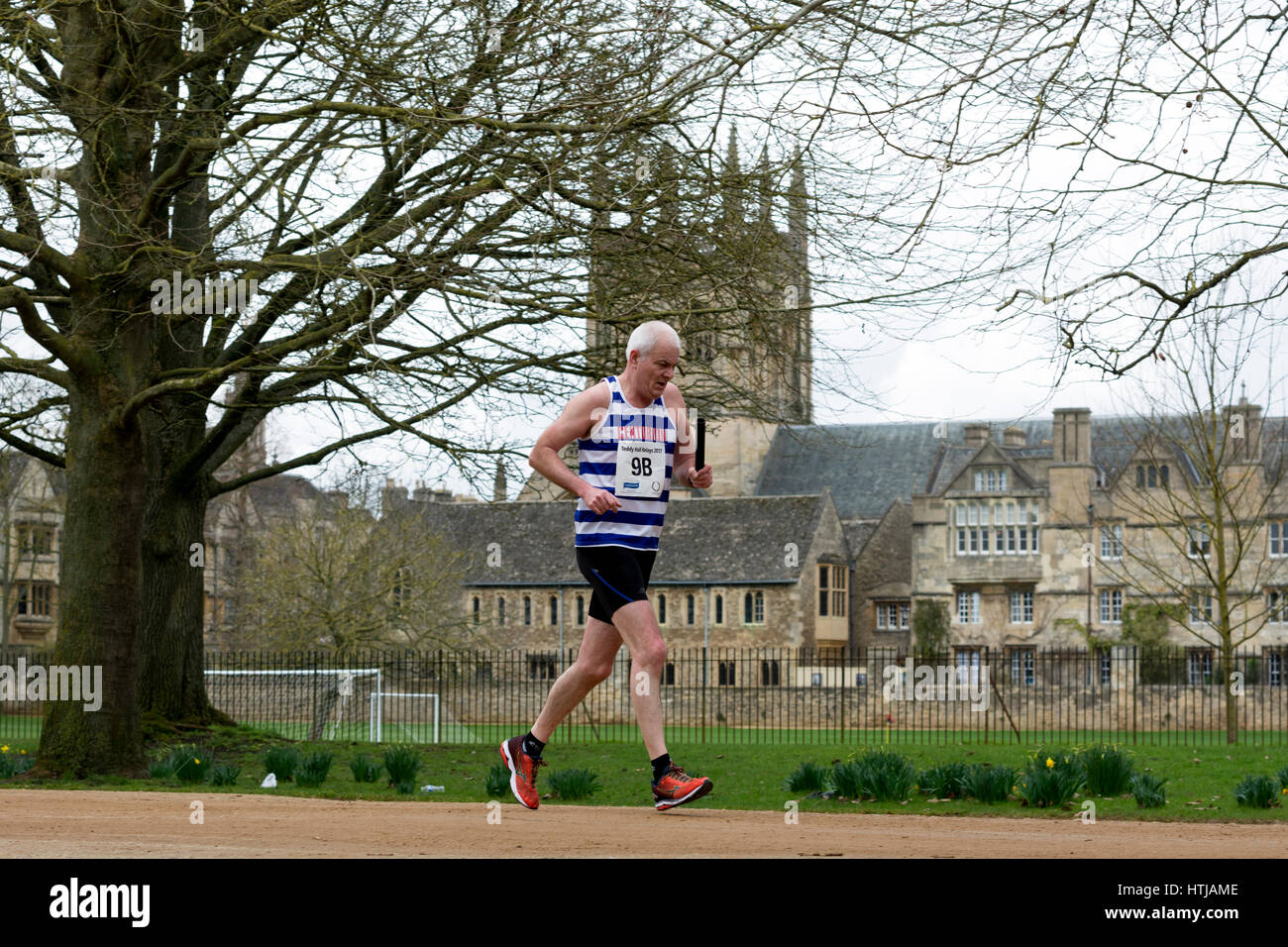 A male club runner passing Merton College Chapel in the Teddy Hall Relays, Oxford, UK Stock Photo
