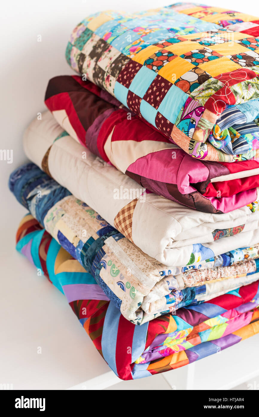 magnificent colored patchwork quilt put by a pile on a white court ...