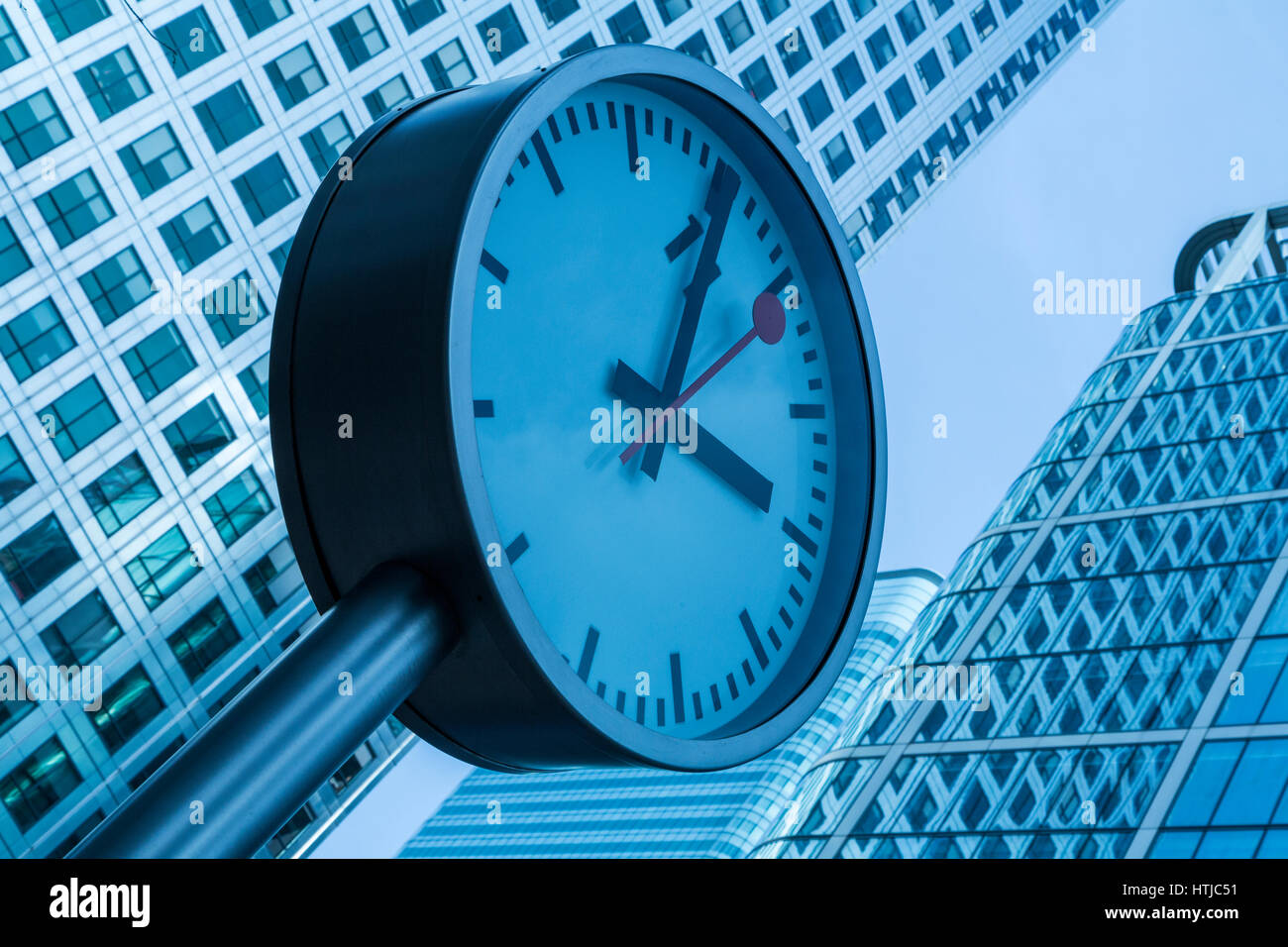 'The clock is ticking' Clock installation with a cold blue tone, and angled ,Canary Wharf, London, England UK Stock Photo